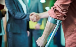 A person on crutches shakes hands with a solicitor
